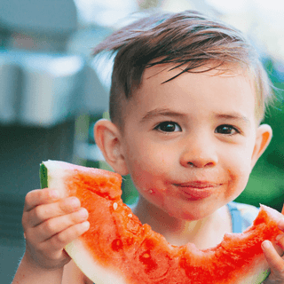 Child eating fruit in Summer